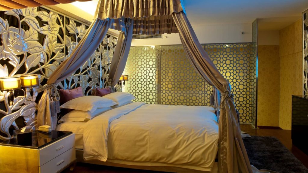 天蓋付きベッドがあるラブホの客室の画像。ゴールドを基調とした高級感のある内装。